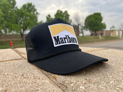 a black trucker hat with a marlboro patch on it